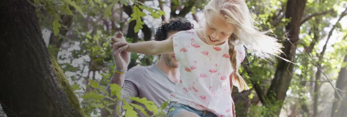 father and daughter playing in forest