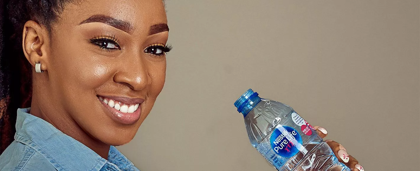 Lady drinking water and a Nestle Pure Life bottle 