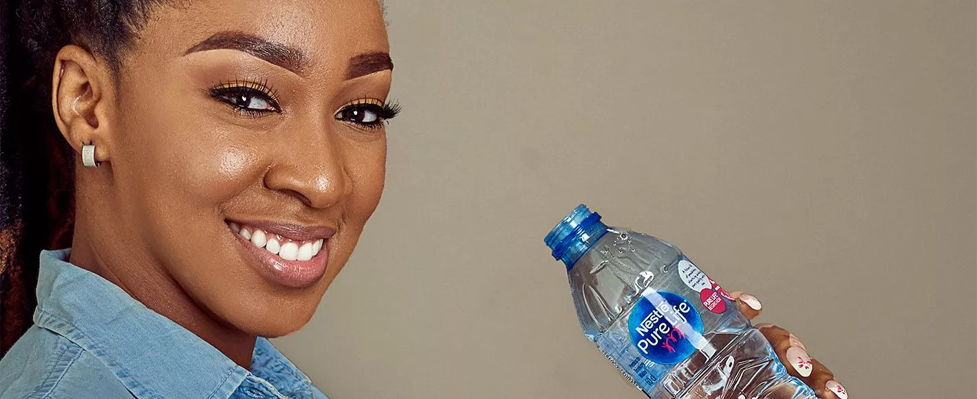 Lady drinking water and a Nestle Pure Life bottle
