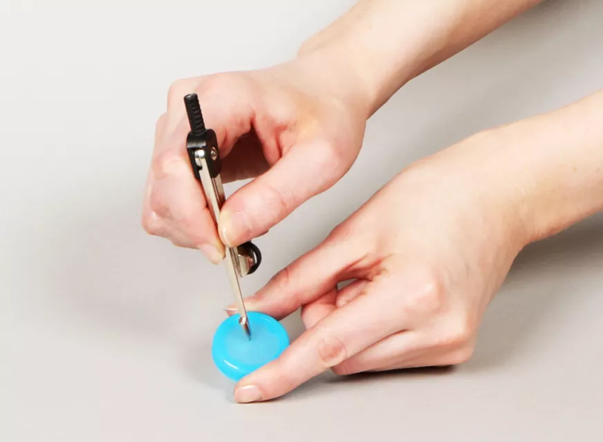 Drilling a hole in a water bottle cap for a water clock craft