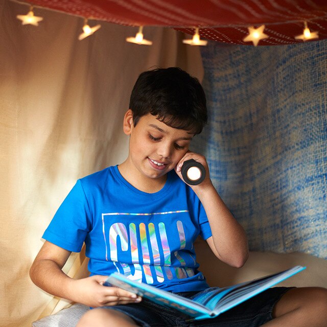 Boy reading book with torch