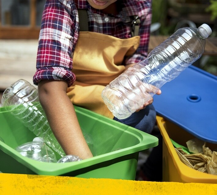 nestle pure life kid picking up disposable water bottles from a green recycling box