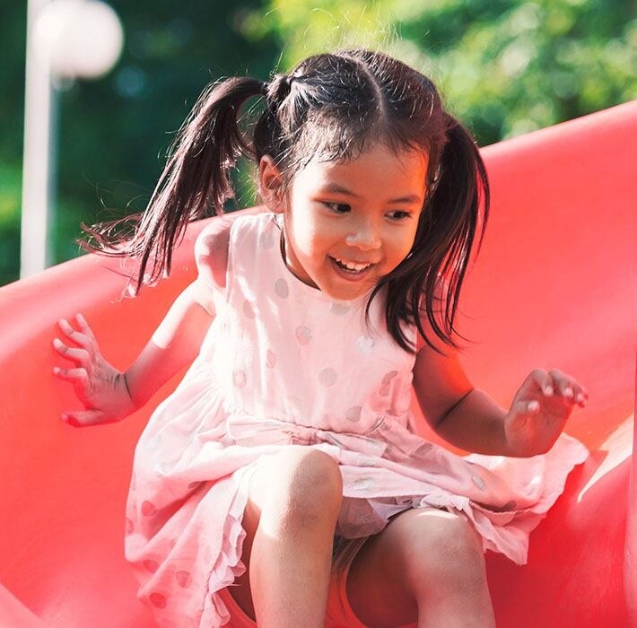 little girl smiling and playing on a slide