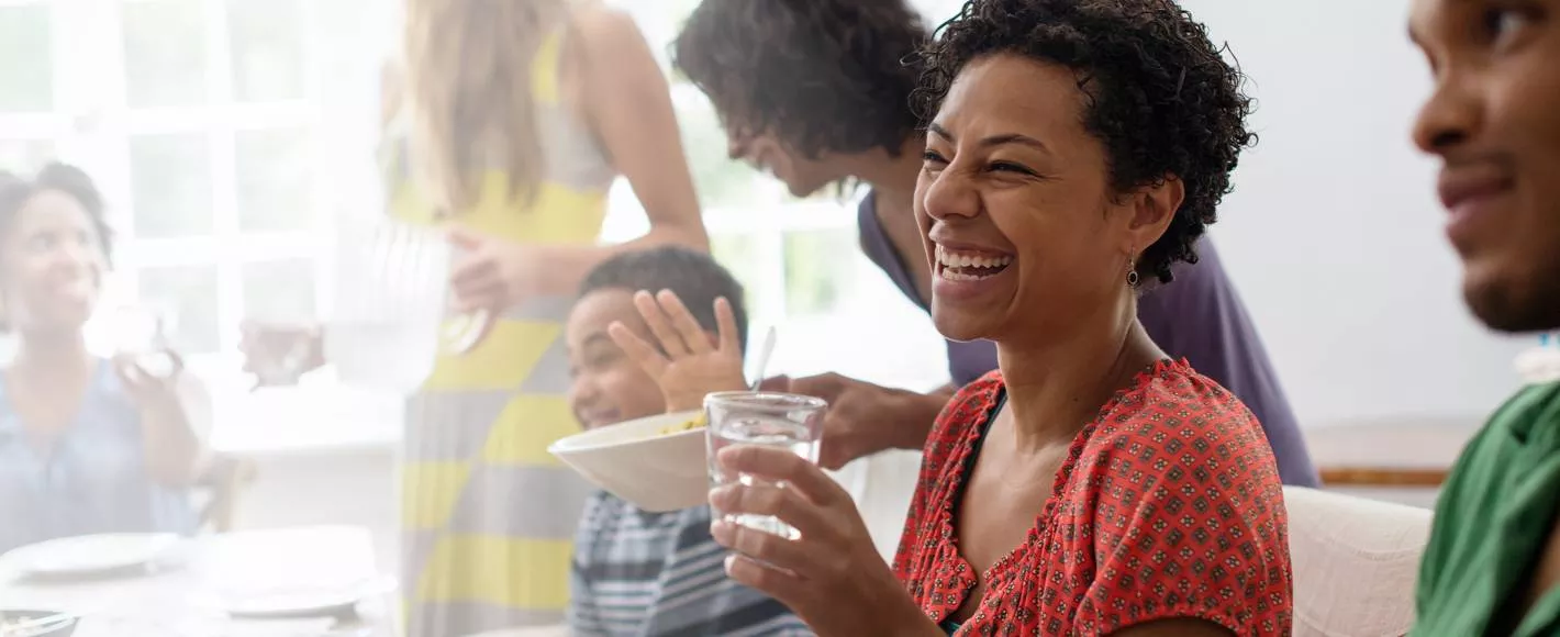 group of people laughing at a dinner party while drinking water