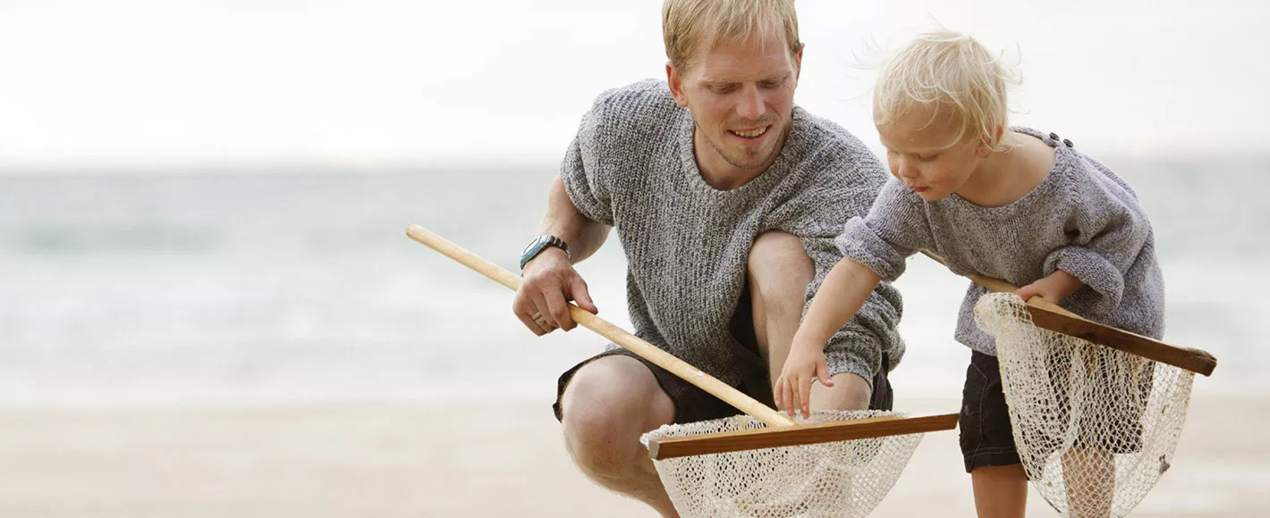 2 Blonde kids playing on the sandy beach with 2 nets