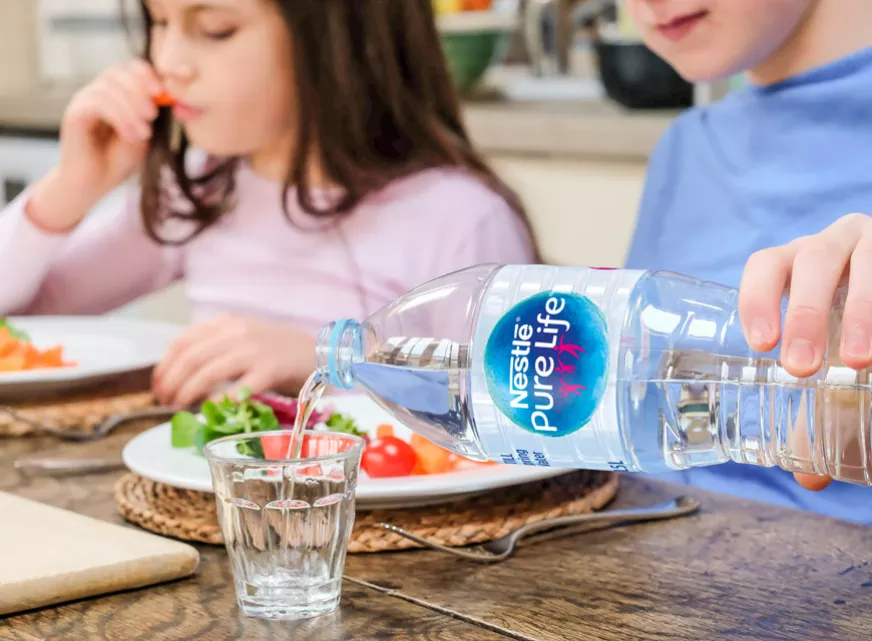 A boy pouring Nestle Pure Life water into a glass